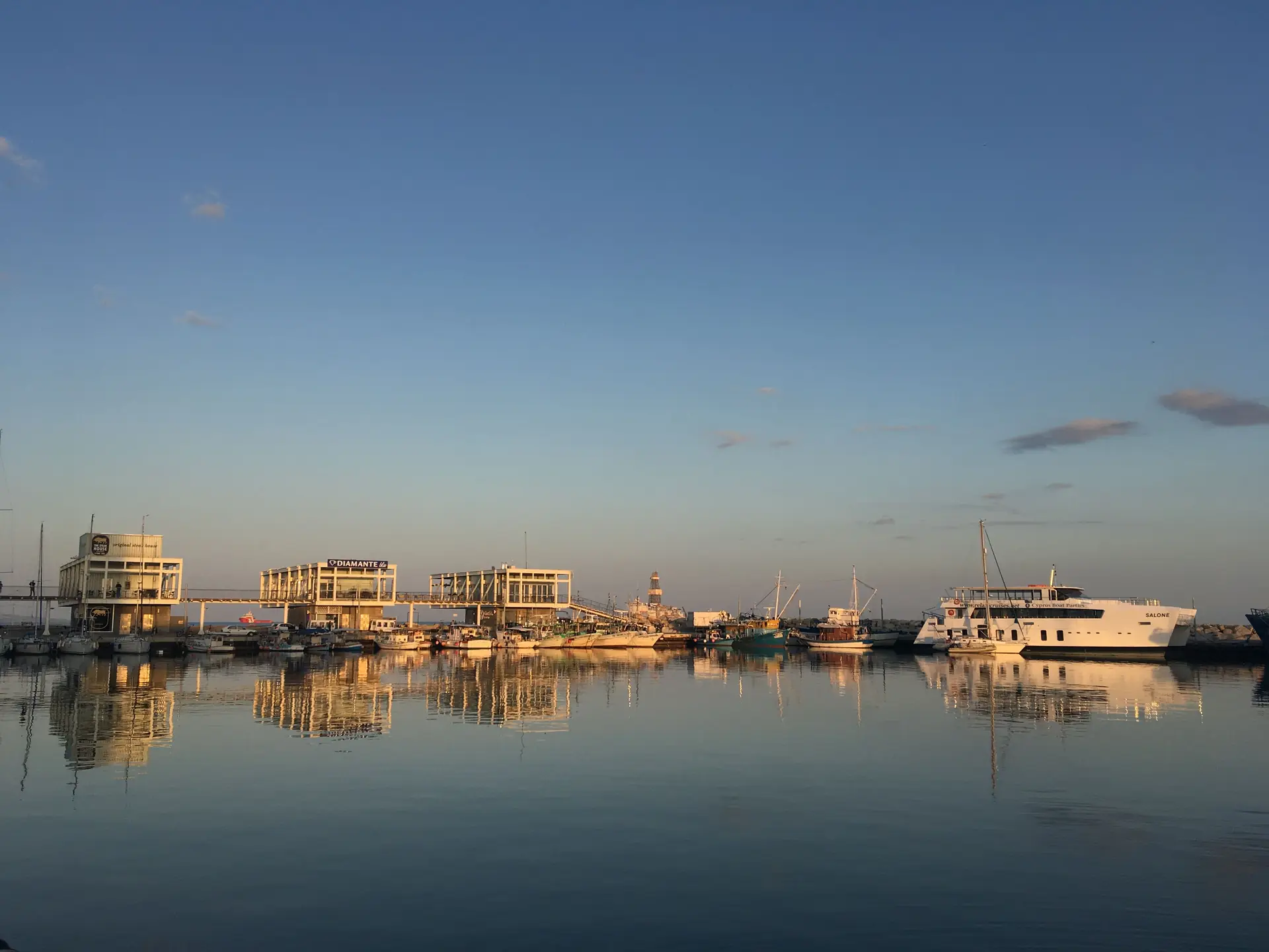 Boats reflected in the calm water of Limassol Marina at dusk